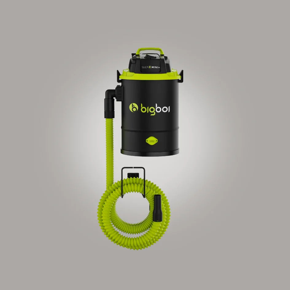 Black and green vacuum cleaner with coiled hose on a gray background