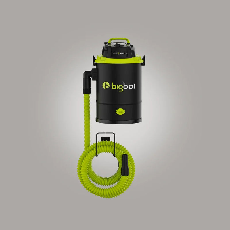 Black and green vacuum cleaner with coiled hose on a gray background